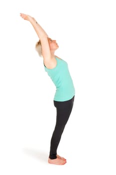 Full-body view of a young blonde woman during yoga exercise "Standing Prevention"" Step 3 against a white background with a slight shadow"