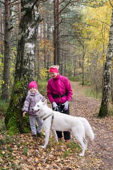 Granny with her granddaughter and a dog walk in autumn Park