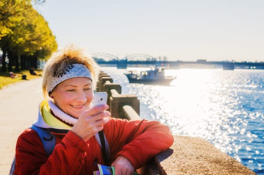 A woman photographs the phone. Embankment in Riga