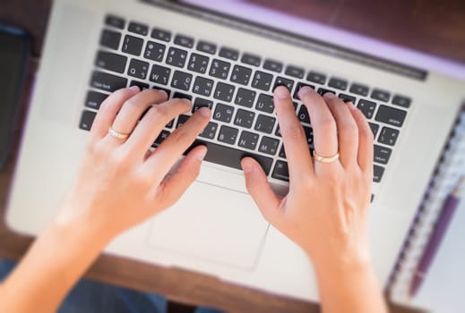 Typing on keyboard laptop top view of wooden table, stock photo