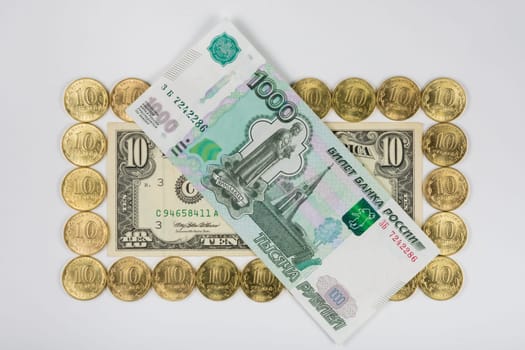 Ten dollars levied on the perimeter of a ten Russian coins lying on top thousand-bill