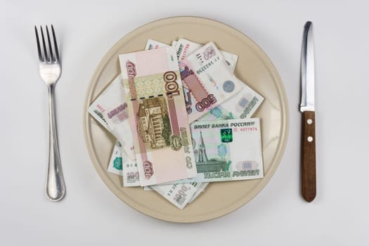 On the plate is a lot of money Russian rubles, lie next to utensils top view
