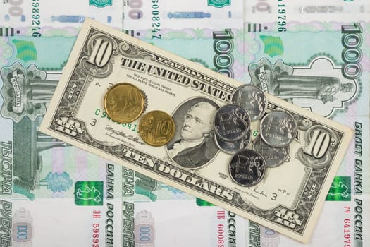Coins ruble and the euro are on the bill of ten dollars which lies on a pile of thousand-Russian banknotes