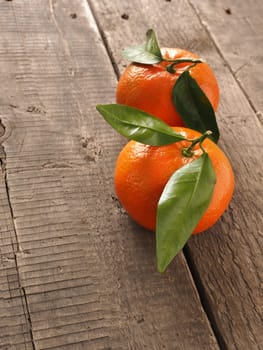 Two fresh organic orange fruits on a rustic wooden table with space for text, natural light