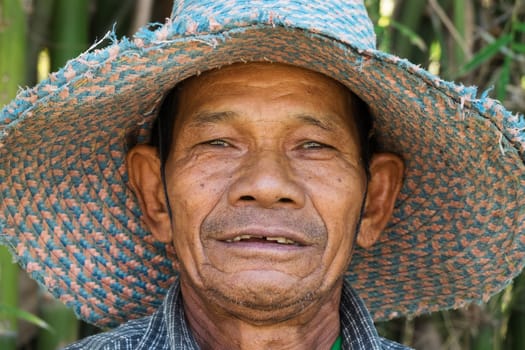 Portrait of an old Asian man with a straw hat