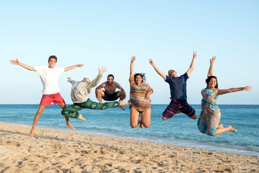 Group of happy teenage friends jumping at the beach