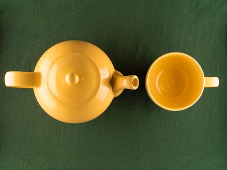 Yellow teapot and mug with tea, simple minimal top view of kitchenware with copy space