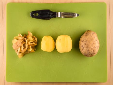 Pattern of sliced peeled potatoes on green used plastic board, simple food preparation illustration, vegetarian dieting, still life with center composition, close up