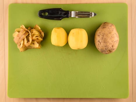Pattern of sliced peeled potatoes on green used plastic board, simple food preparation illustration, vegetarian dieting, still life with center composition, close up