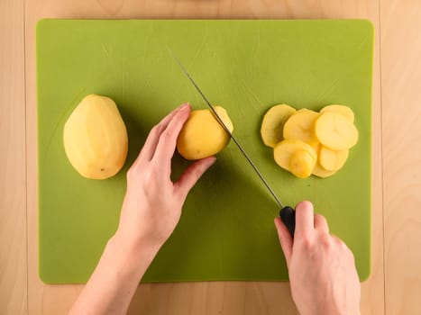 Pattern of sliced peeled potatoes on green used plastic board, simple food preparation illustration, vegetarian dieting, still life with center composition, close up