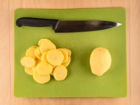 Pattern of sliced peeled potatoes on green used plastic board, simple food preparation illustration, vegetarian dieting, still life with center composition, close up