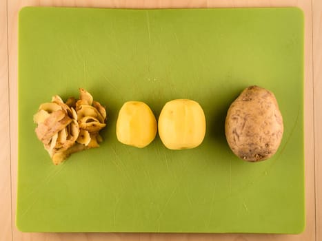 Pattern of sliced peeled potatoes on green used plastic board, simple food preparation illustration, vegetarian dieting, still life with center composition, close up