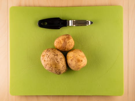 Pattern of sliced peeled potatoes on green used plastic board, simple food preparation illustration, vegetarian dieting, still life with center composition, close up