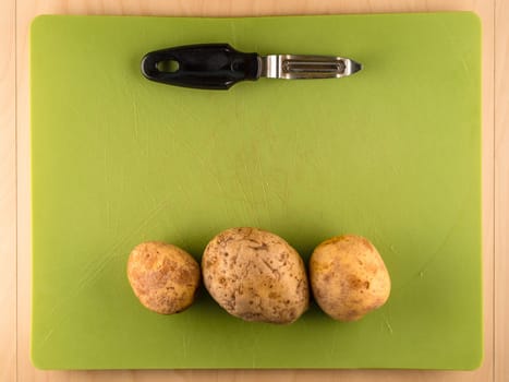 Pattern of sliced peeled potatoes on green used plastic board, simple food preparation illustration, vegetarian dieting, still life with center composition, close up