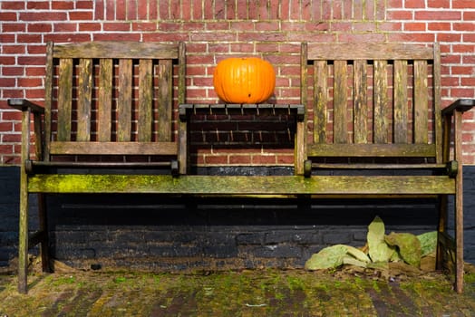 Pumpkin standing on vintage wooden table and chairs against brick wall, Halloween concept