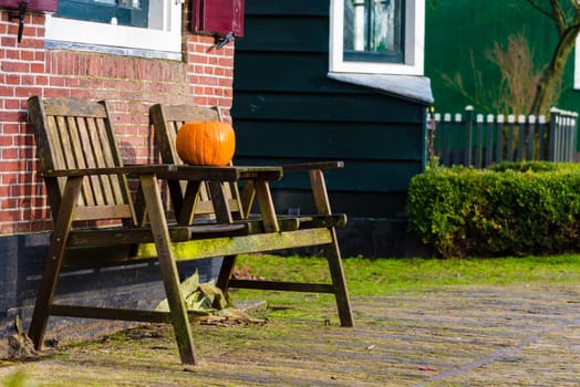 Pumpkin standing on vintage wooden table and chairs against brick wall, Halloween concept