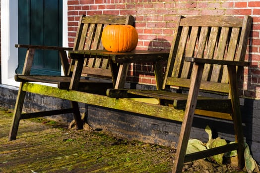 Pumpkin standing on vintage wooden table and chairs against brick wall, Halloween concept