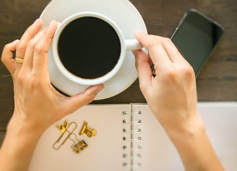 Hot cup of coffee on wooden work table, stock photo
