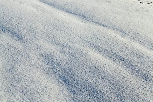 covered with white snow drifts surface. Photo closeup. On snow formed irregularities. Photo close-up, small depth of field