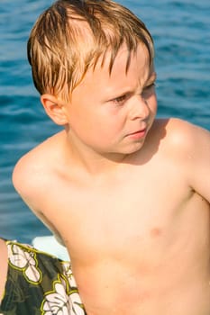 cute boy on a boat is angry and makes a grimace