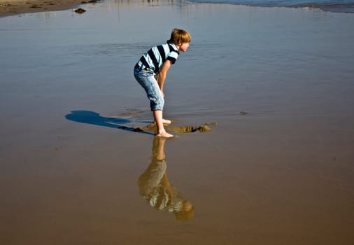 boy at the beach in Venice with reflecting picture in wet sand