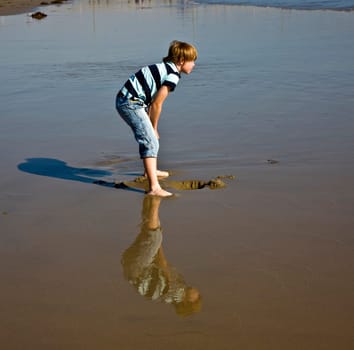 boy at the beach in Venice with reflecting picture in wet sand