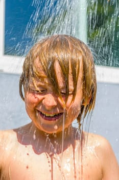 child has a refreshing shower in the garden