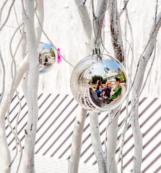 white painted branches give a harmonic background with chrismas tree balls and mirroring of a family