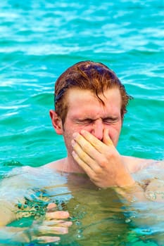 teenage boy blows his nose  of saltwater in the ocean