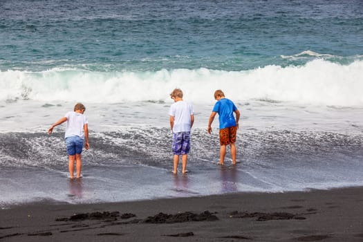 boys have fun at the black volcanic beach