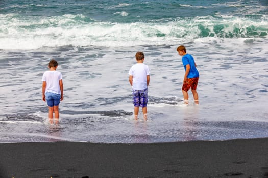boys have fun at the black volcanic beach
