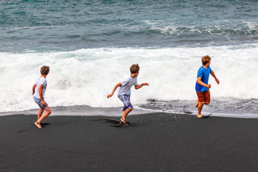 boys have fun at the black volcanic beach