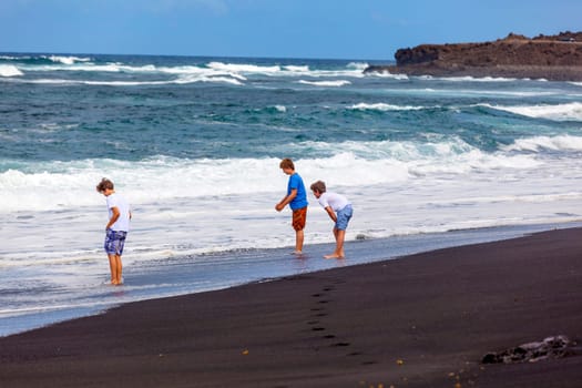 boys have fun at the black volcanic beach