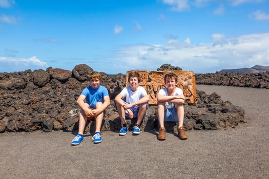 three friends sitting on a rock and have a rest