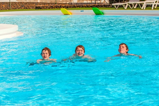 three friends swimming in a row in the pool