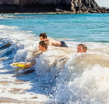 boys have fun riding in the waves