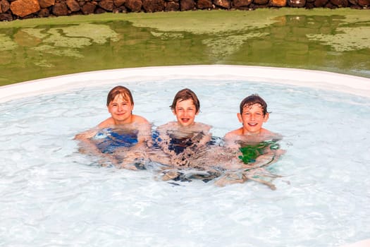three friends have fun joking in the pool