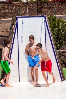 cute boys have fun unter the pool shower
