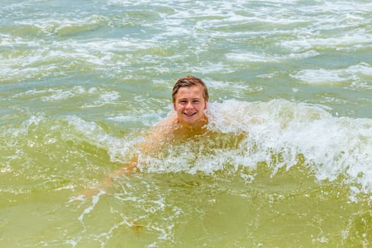 handsome boy enjoys swimming in the ocean