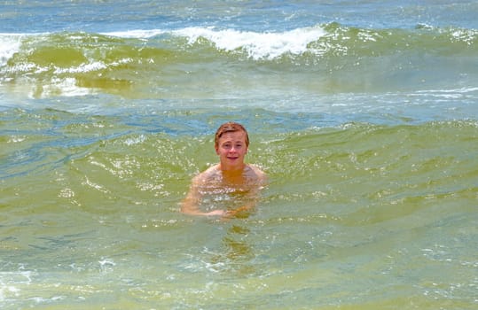 handsome boy enjoys swimming in the ocean