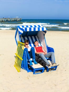 teens enjoy sunbath in the roofed wicker beach chair
