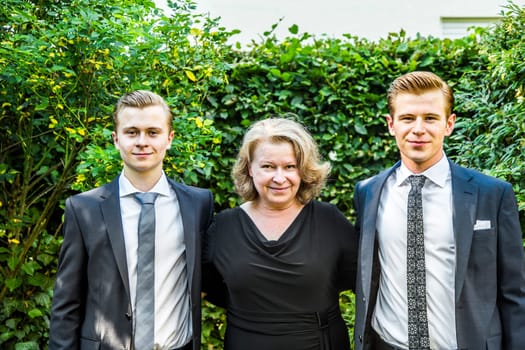 portrait of mother with her two adolescent sons, dressed in suit with tie