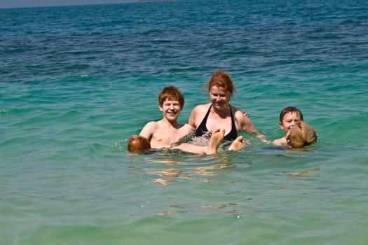 family  is playing with a coconut in the sea on a beautiful beach