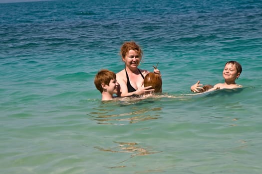 family  is playing with a coconut in the sea on a beautiful beach