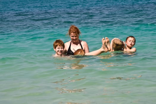 family  is playing with a coconut in the sea on a beautiful beach