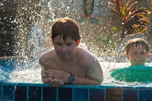 children are playing in a pool and spottering with water