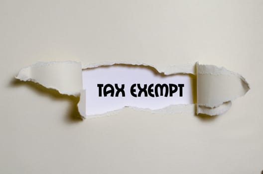 The word tax exempt appearing behind torn paper