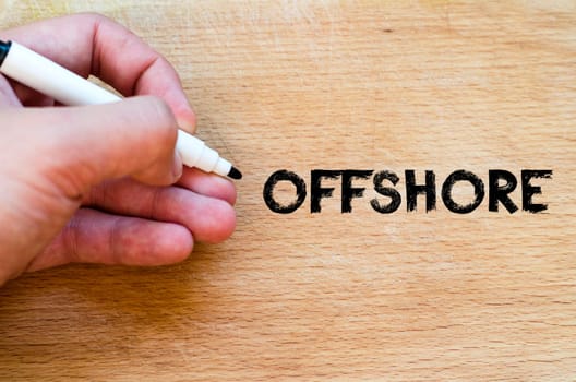 Human hand over wooden background and offshore text concept