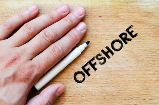 Human hand over wooden background and offshore text concept