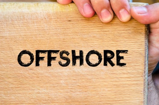 Human hand over wooden background and offshore text concept